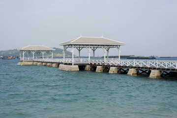 White Long wooden bridge pavilion into the sea, Cargo ships in the sea.