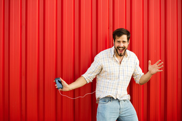 adult man with cellphone dancing on red background