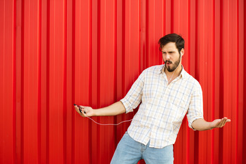 adult man with cellphone dancing on red background