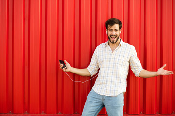 adult man with cellphone dancing on red background