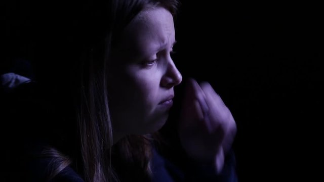 Depressed teen girl is crying in the dark. 4K UHD.