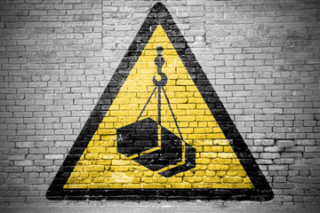 Ziegelsteinmauer mit Warnzeichen Warnung vor schwebender Last Graffiti