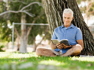 Senior man sittingin park while reading book