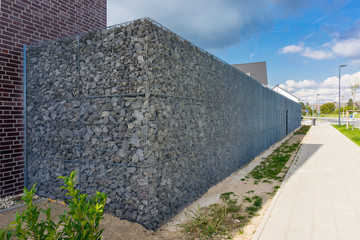 Hohe Gabionenmauer als Sicht- und Lärmschutz zum öffenlichen Raum