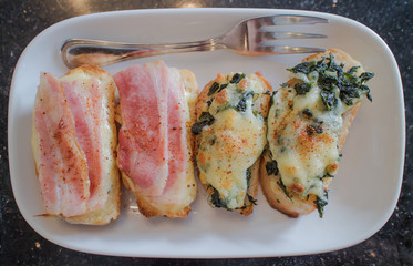 Garlic cheese bread topping with bacon and spinach on white plate