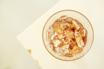 Top view close-up glass of cola with ice cube.