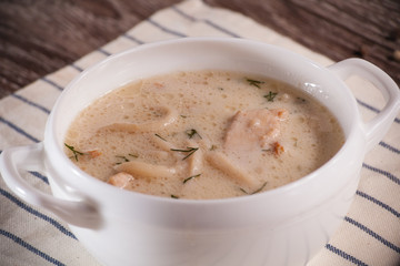 Fototapeta na wymiar Tom Kha soup in white plate underneath flax towel on wooden back