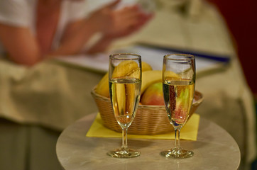 Two glasses of sparkling wine in hotel room with woman in backgr