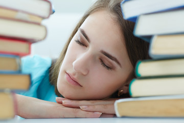 Portrait of a tired student girl sleeping on the books.