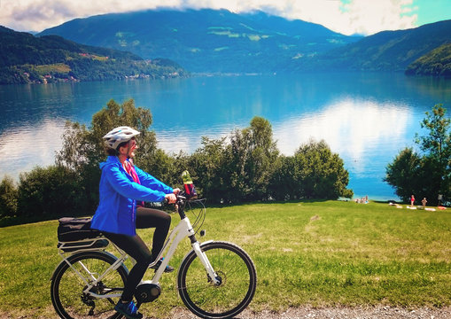 woman cycling on an electric bike beside a beautiful lake/biking