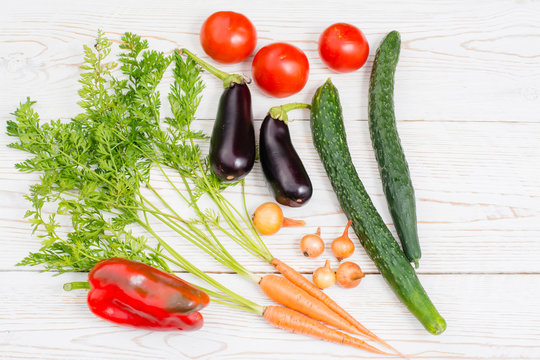 Помидоры, огурцы, баклажаны, болгарский перец, морковь, репчатый лук на деревянном фоне