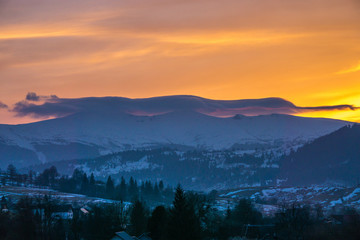 Obraz premium landscape at sunset dusk picturesque view little town at valley surrounded by mountains with blue sky and lonely cloud