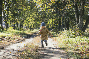 Fototapeta premium Сhild girl in warm jacket and hat in the autumn in the Park