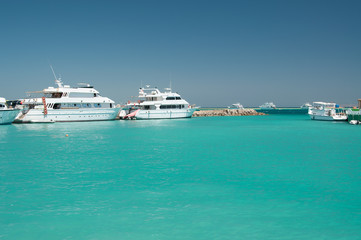 few white yacht near coral reef in the calm blue sea blue cloudless sky