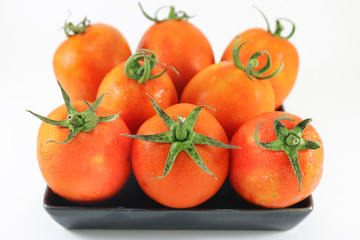 Tomato in black dish on on white background isolated.