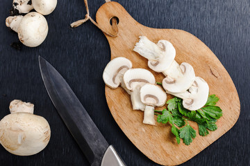 champignon mushroom with parsley and knife  over wooden cutting