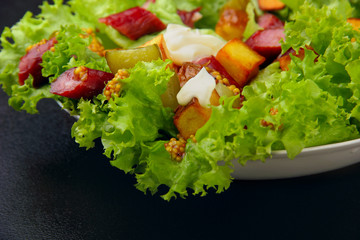 Salad.Chorizo sausage, lettuce, pickled cucumber fried potato with mayonnaise.Dark background