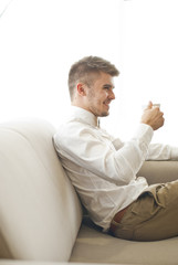 Fototapeta premium Handsome attractive young guy drinking coffe in the room 