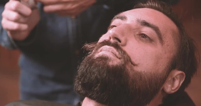 Barber grooming mustache with wax in barbershop 4k close-up video. Bearded lumberjack style man