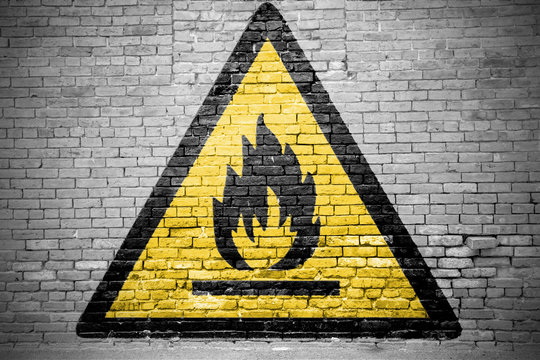 Ziegelsteinmauer mit Warnzeichen Warnung vor feuergefährlichen Stoffen Graffiti