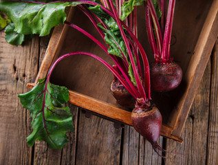 Young,fresh beets with tops on old wooden background.Toned image.Vintage style.selective focus.