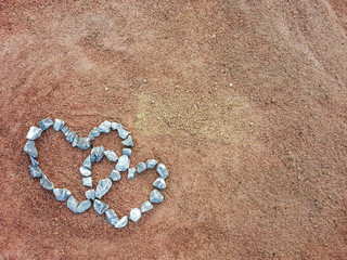 Stones arranged in a heart shape on the sand.