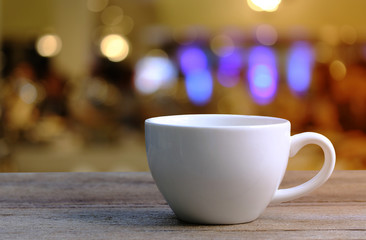 White Coffee cup on wooden table in coffee shop blur background.