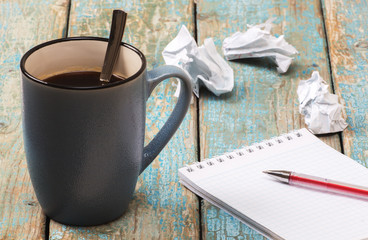 Blank notebook and cup of coffee on the wooden table