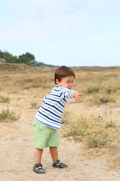 Happy Little Kid Throwing Sand In A Path Among Dunes