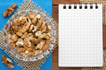 Menu background. Cook book. Recipe notebook with walnuts on a blue background and a wooden board.