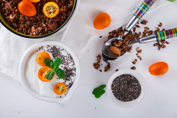 Yogurt with kumquats ,Chia seeds,and granola on a white background.Healthy food or diet concept.selective focus.