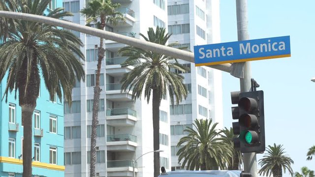 Santa Monica sign on a traffic light pole, palm trees in the background