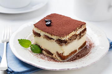 Tiramisu, traditional Italian dessert on a white plate