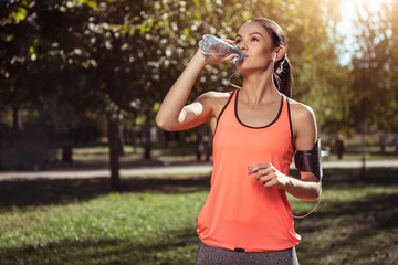 Delighted girl drinking water after morning exercises