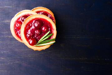 Winter one bite-sized snack or dessert: tartlets with sweet and sour cranberry sauce (jam), decorated with rosemary. Top view, copy space
