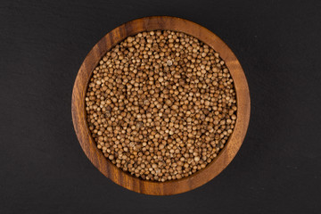 Coriander seeds in  small wooden bowl