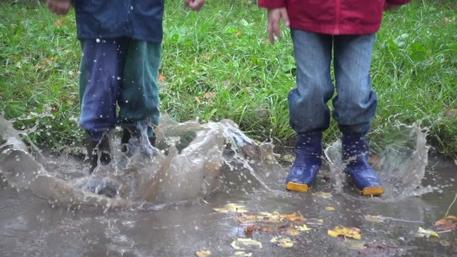 Two boys jumping in muddy puddle, slow motion 250 fps