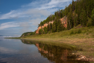 River bank with reflection in water. Lena River, Yakutia, Russia.