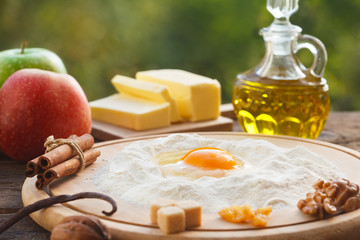 Ingredients for dough for an apple pie. Flour and eggs on wooden board.