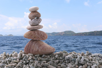 Balance stone on pile rock with sea background.