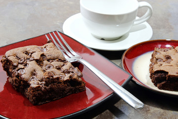 Chocolate chip brownie in a plate with milk and chocolate chips