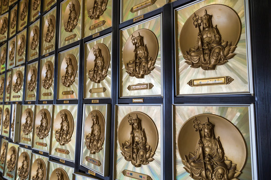 Closeup of a wall full of gold-framed drawers that contain ashes of the deceased, each with image of a Buddha in columbarium at the Ten Thousand Buddhas Monastery (Man Fat Tsz) in Sha Tin, Hong Kong.