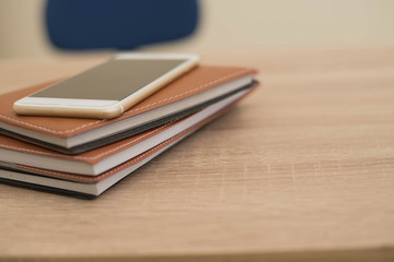 smart phone over notebook and pen on the wooden table background