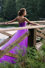 Naklejka premium Beautiful girl in violet dress among in the garden