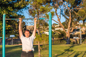 Fit muscular man doing pull ups in outdoor park