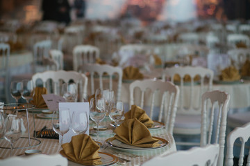 Round dinner tables served with rich plates and glassware
