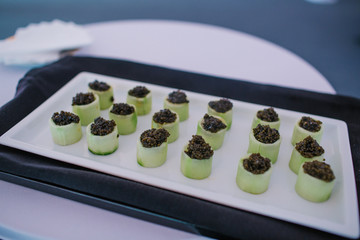 Green snacks with caviar stand on the white dish