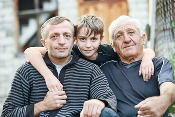 Grandfather with his son and grandson near country house