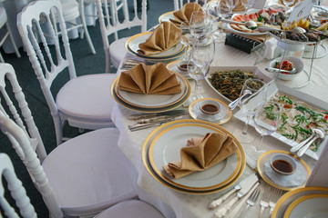 Luxurious dinner table served with plates with golden design