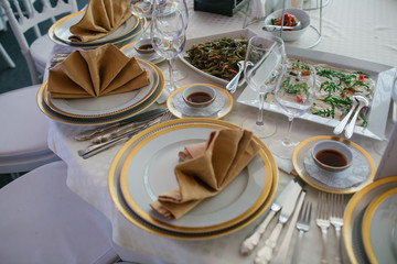 Bowls with sauce stand between dinner plates on the round table